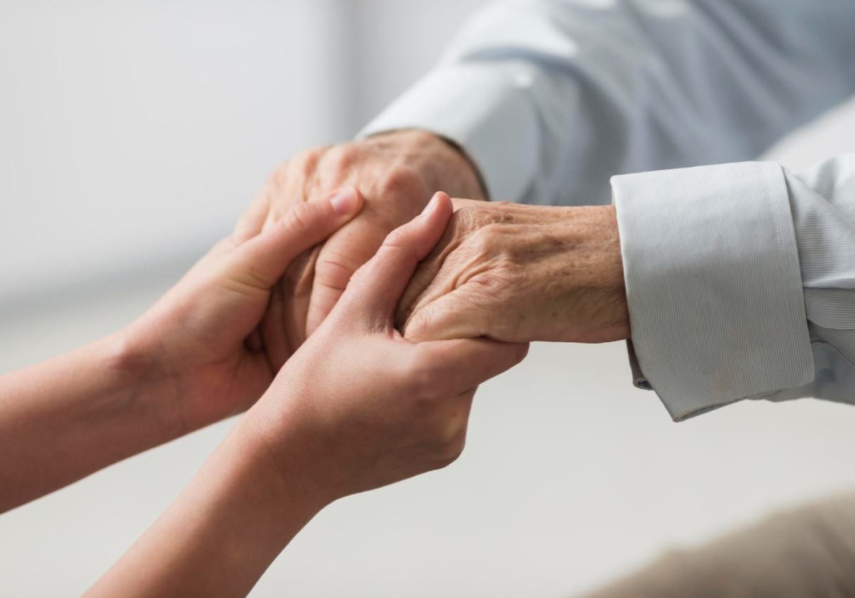 Nurse holding senior man's hands for sympathy